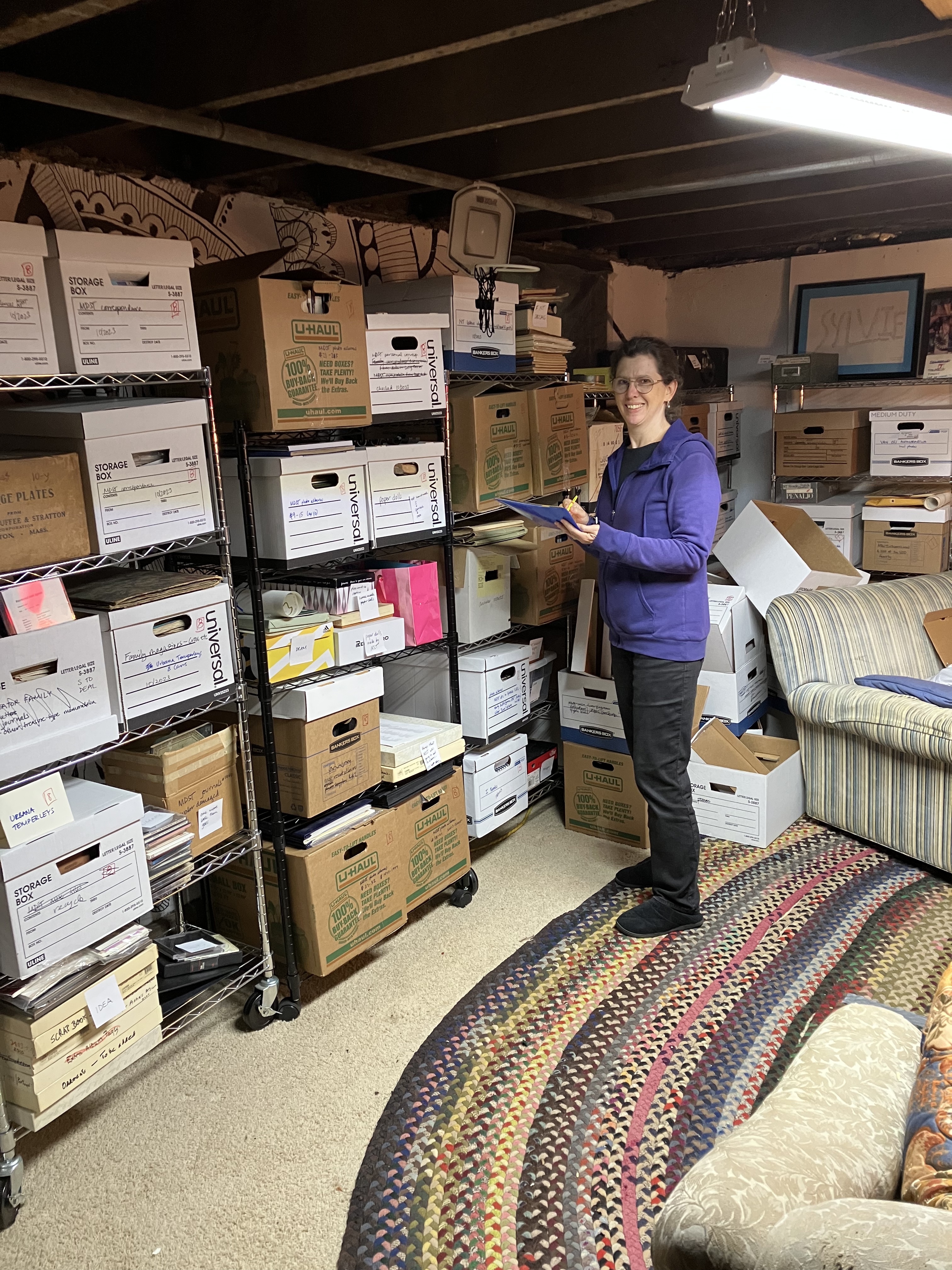 Sylvie Khan working in a home with banker boxes and temporary shelving.